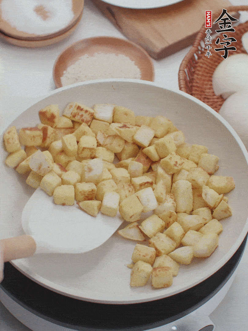 起鍋熱油，倒入饅頭丁，小火煎至蛋液凝固定型再翻面，饅頭丁部煎至金黃時(shí)盛起待用。