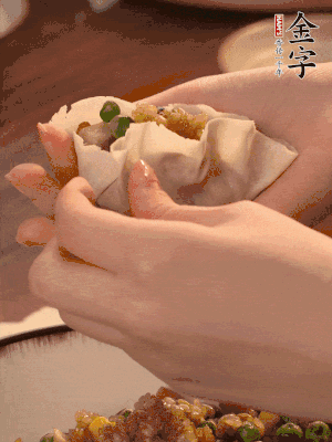 取一大勺餡料放進(jìn)餃子皮里，用大拇指按住頂部餡料，再用虎口掐出形狀。